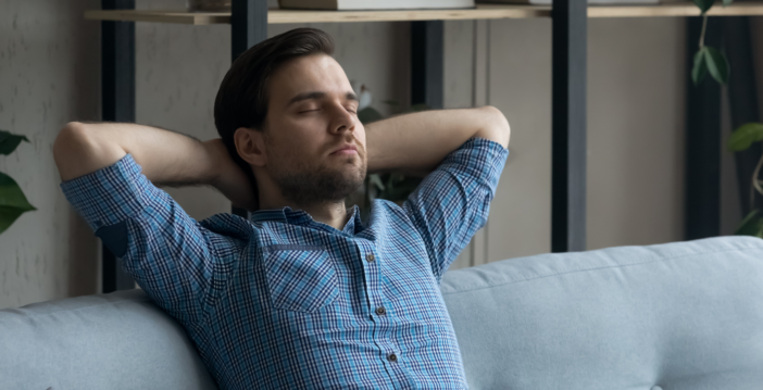 Man zit op de bank met zijn ogen dicht