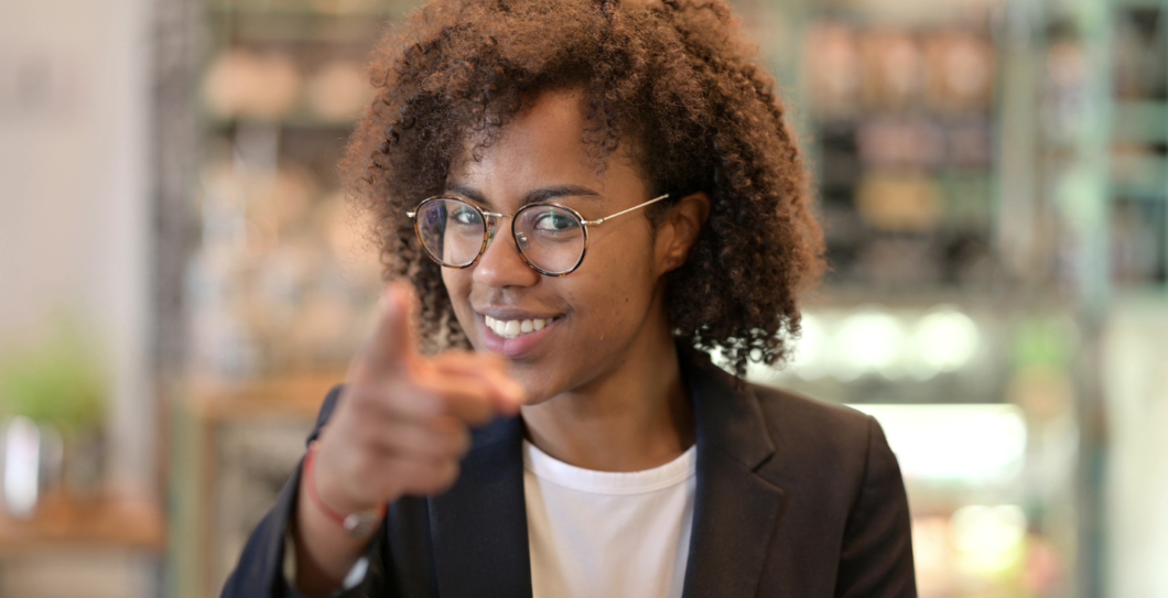 vrouw kijkt lachend in de camera met een wijzende vinger