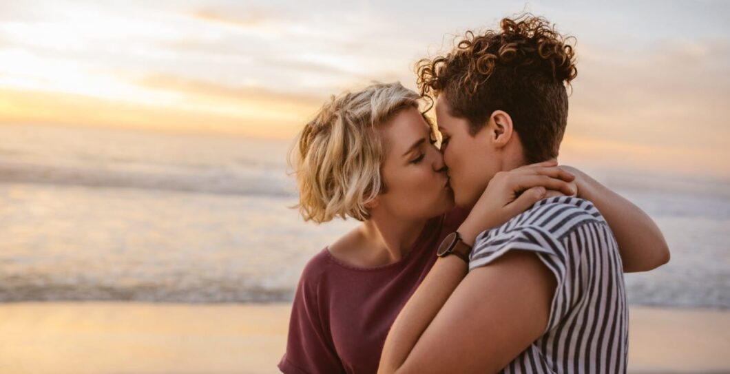 twee vrouwen kussen elkaar op het strand