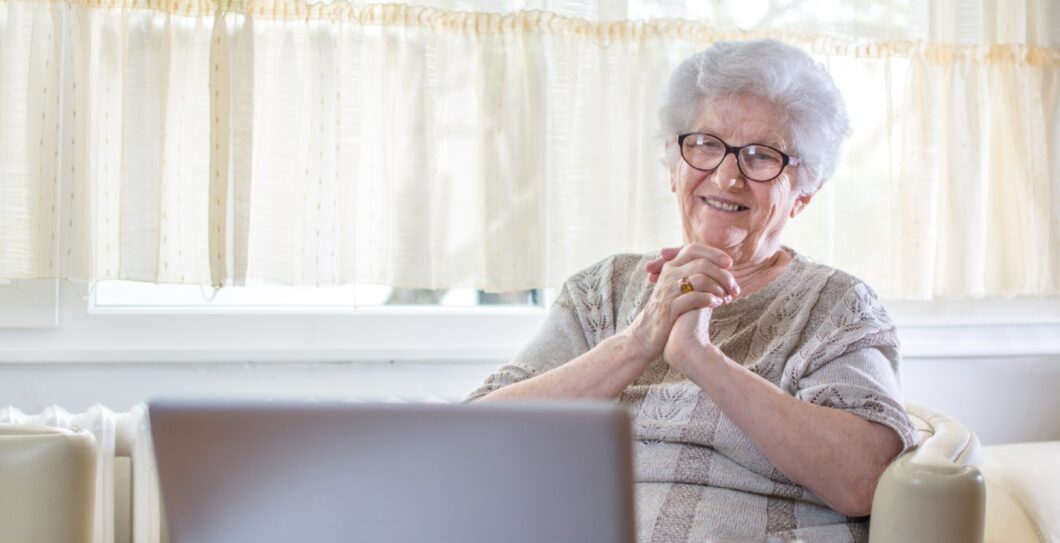 oudere vrouw maakt gebruik van laptop en lacht