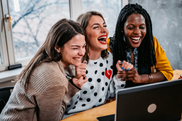 drie schaterlachende vrouwen achter een laptop