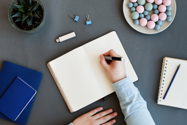 hand schrijft in notitieboek|man plakt post-it notes op een muur