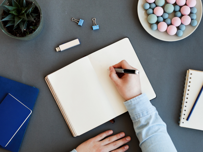 hand schrijft in notitieboek|man plakt post-it notes op een muur