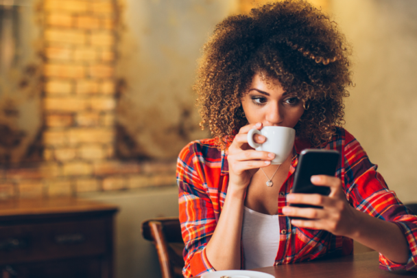 vrouw drinkt koffie en gebruikt haar smartphone