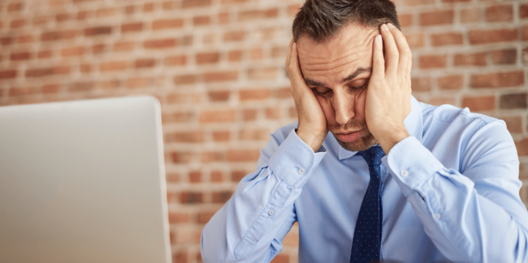 man achter laptop heeft last van stress