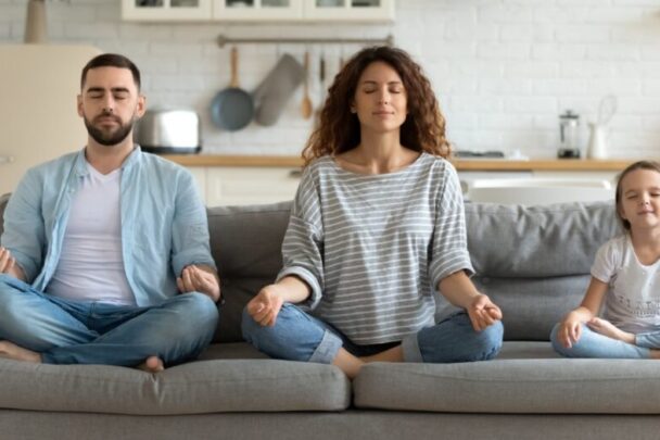 gezin van man vrouw en kind doet een meditatie op de bank