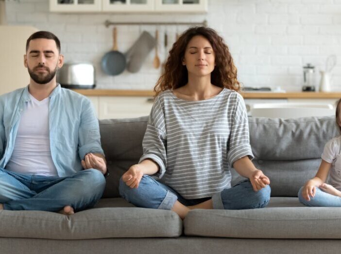 gezin van man vrouw en kind doet een meditatie op de bank