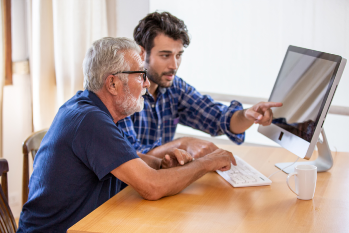 man legt iets uit aan andere man over zijn computer