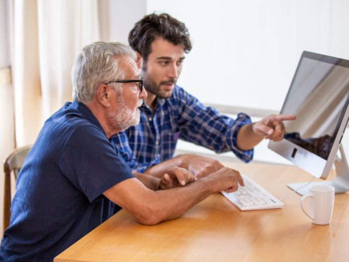 man legt iets uit aan andere man over zijn computer