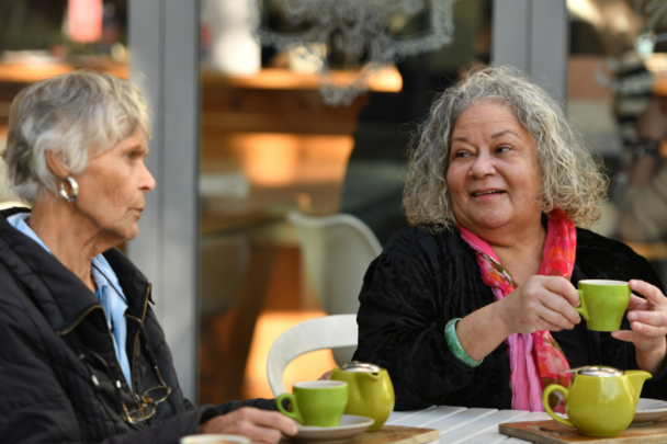 twee vrouwen met een kopje koffie die samen zitten te kletsen