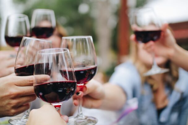 Groep mensen proost met een glas rode wijn.