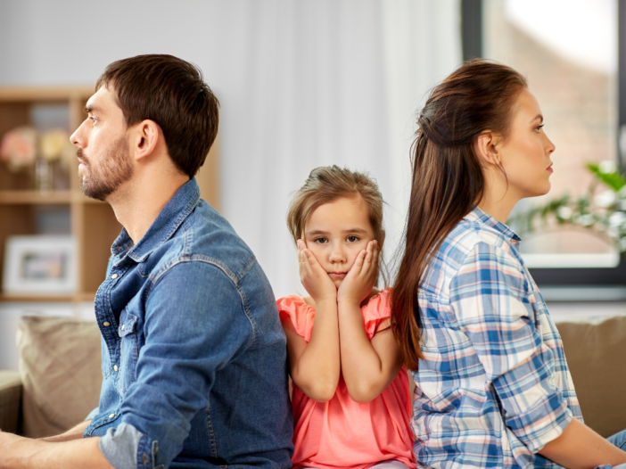 man en vrouw met ruggen naar elkaar, met tussen hen in een kind