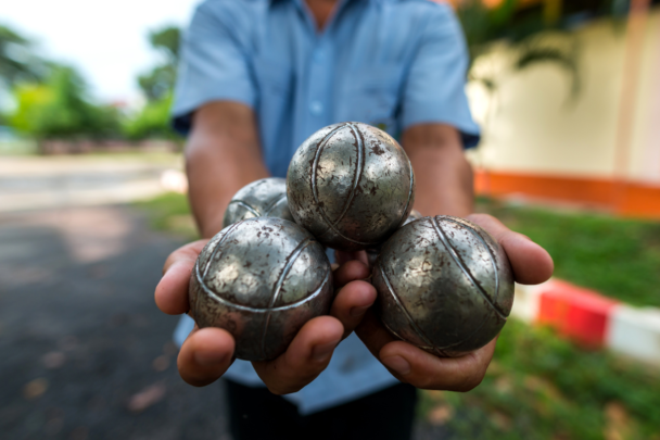 man houdt 3 jeu des boules ballen vast