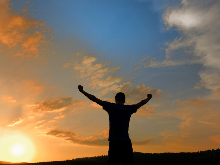 man staat met armen in de lucht in een power pose