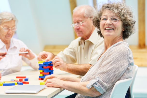 drie ouderen spelen het spelletje Jenga