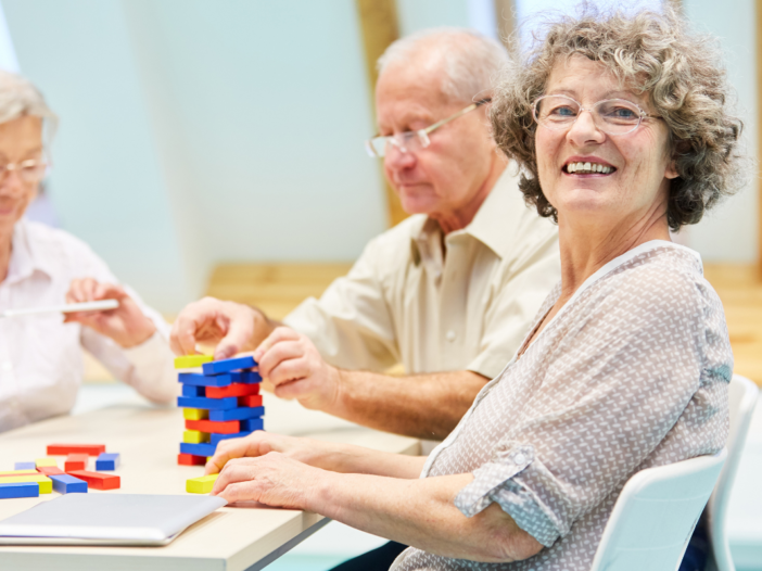 drie ouderen spelen het spelletje Jenga