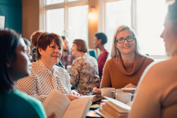 vrouwen lezen samen een boek aan tafel