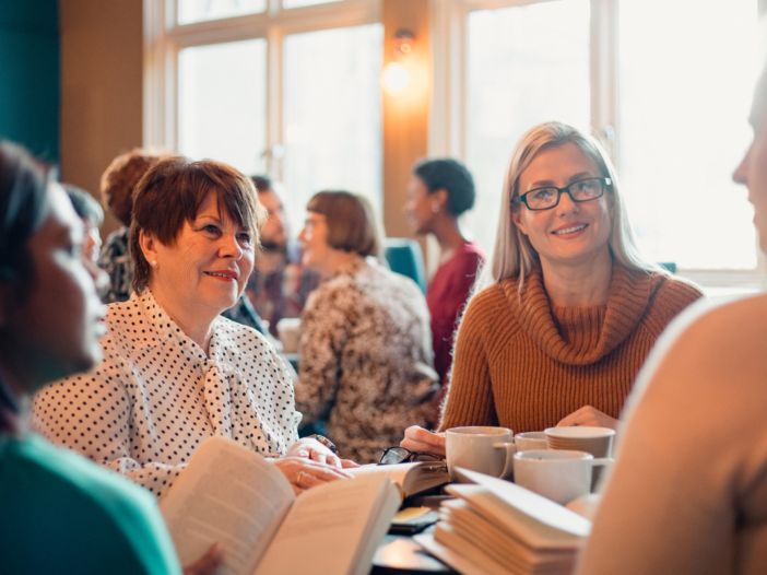 vrouwen lezen samen een boek aan tafel