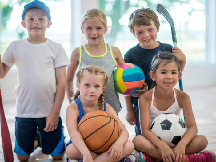 Vijf kinderen poseren voor een foto in sportkleding