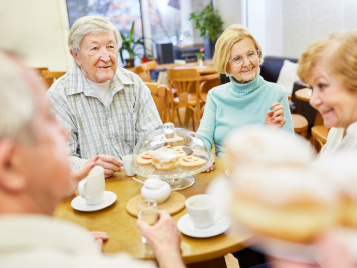 Oudere dames en heer eten samen een maaltijd