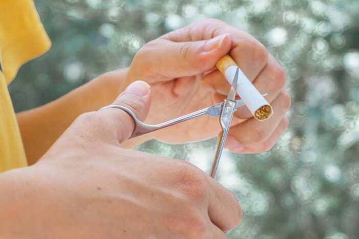 Vrouwenhanden knippen een sigaret door.