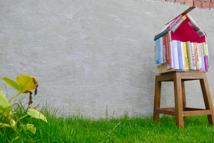 een minibilbiotheek gemaakt van gestapelde boeken, op een grasveldje