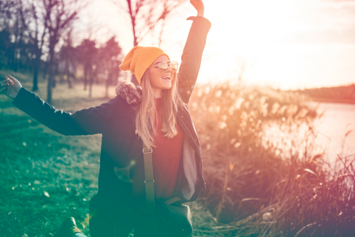 vrouw staat op een grasveld met op de achtergrond een opkomende zon