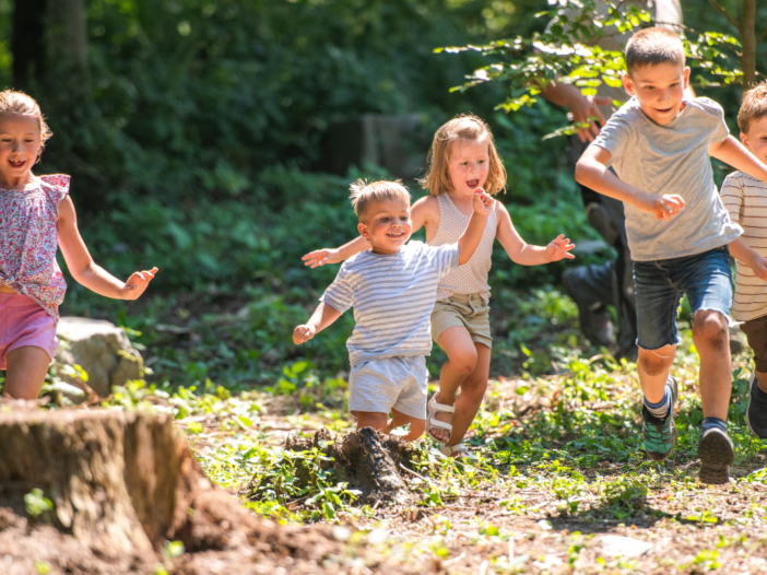 Kinderen rennen in het bos. De zon schijnt en het zijn kleine kinderen.