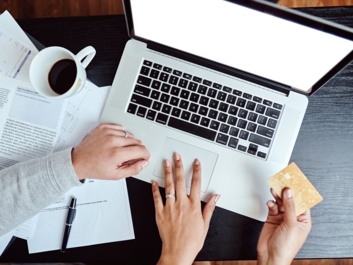 Man en vrouw zitten samen achter de laptop. De vrouw heeft een geldbriefje in haar hand en ze zijn samen de geldzaken aan het regelen en bekijken.