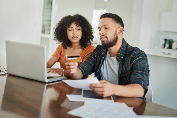 Mensen met schulden die naar hun geldzaken kijken. Voor hun laptop met hun bankpas in hun hand