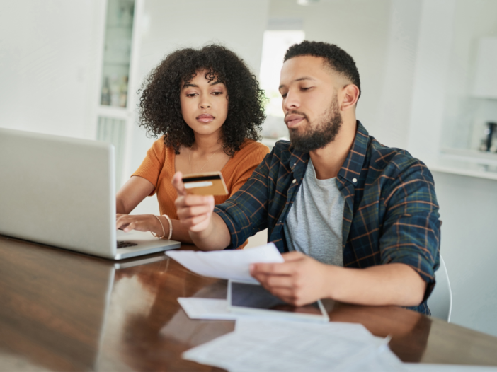 Mensen met schulden die naar hun geldzaken kijken. Voor hun laptop met hun bankpas in hun hand