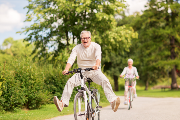 Een senioren man die op zijn fiets zit. Achter hem fietst iemand anders van de fietsclub.