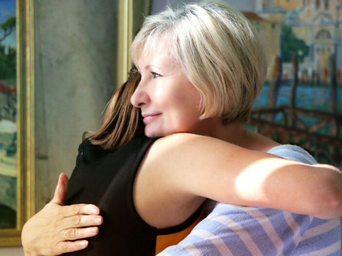 Blonde vrouw geeft een andere vrouw een knuffel. Een knuffel om de ander te steunen.