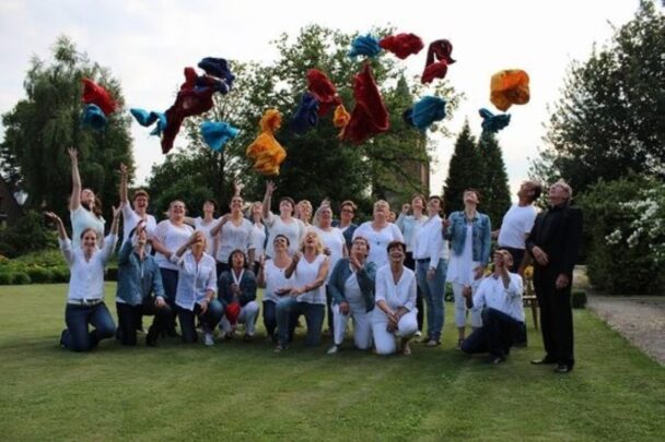 Dit is de zanggroep multivoices in duizel. Ze hebben allemaal witte kleren aan en gooien spullen de lucht in.