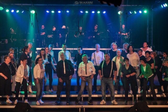 Dit is de zanggroep van Hulsel. Mannen en vrouwen door elkaar op een podium die allemaal zingen samen.