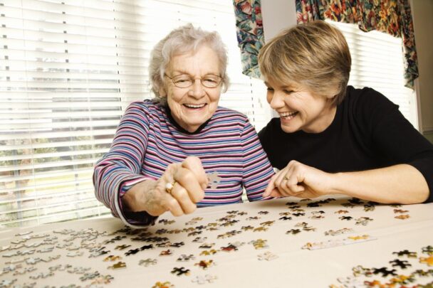 Een oudere vrouw legt samen met een jonge vrouw een puzzel