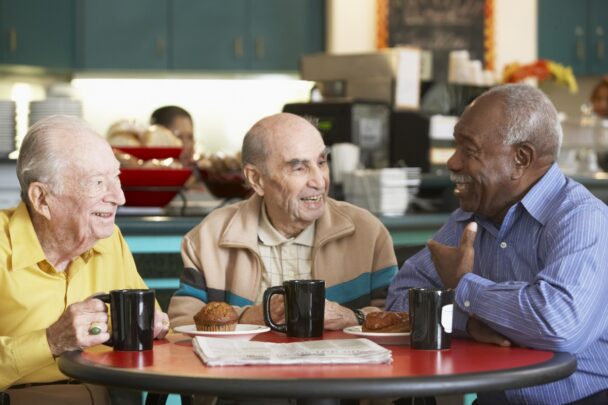 Drie oudere heren drinken samen koffie en hebben een gezellig gesprek