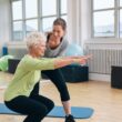 Oudere vrouw traint samen met een jongere vrouwelijke coach in een sportzaal.