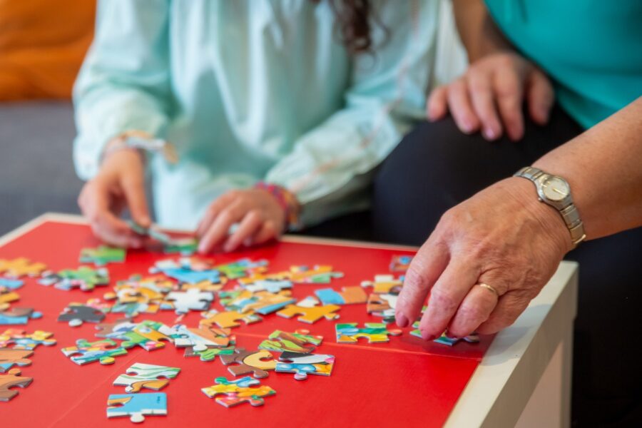 Oudere dame legt een legpuzzel samen met een jongere vrouw