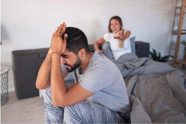 Man en vrouw maken ruzie. De vrouw schreeuwt naar de man en de man zit met zijn hoofd in zijn handen.