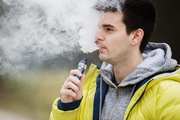 Man met gele jas is buiten aan het vapen