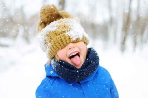 Kleine jongen met wintermuts op staat in de sneeuw