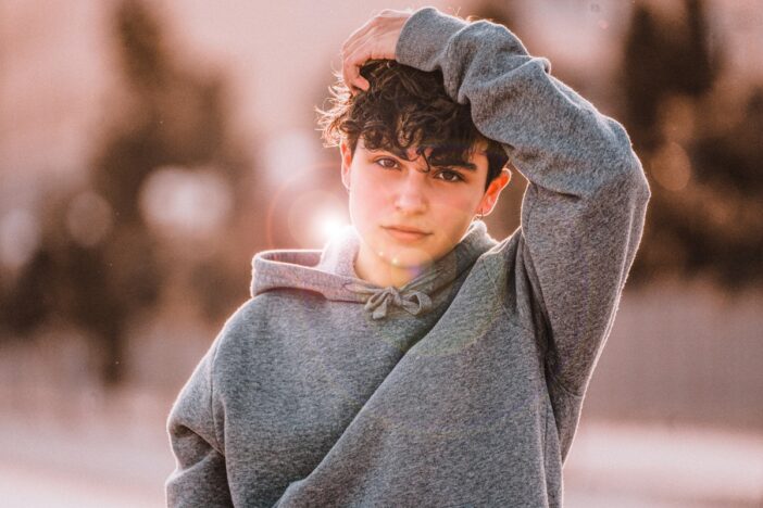 Puberjongen met grijze hoodie en donker haar.