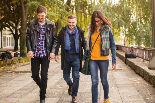 Twee mannen en een vrouw wandelen samen over straat.