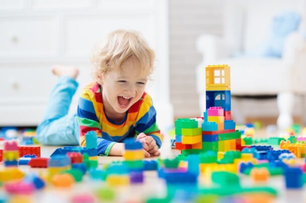 Kindje speelt met vrolijk gekleurde blokken op de grond.