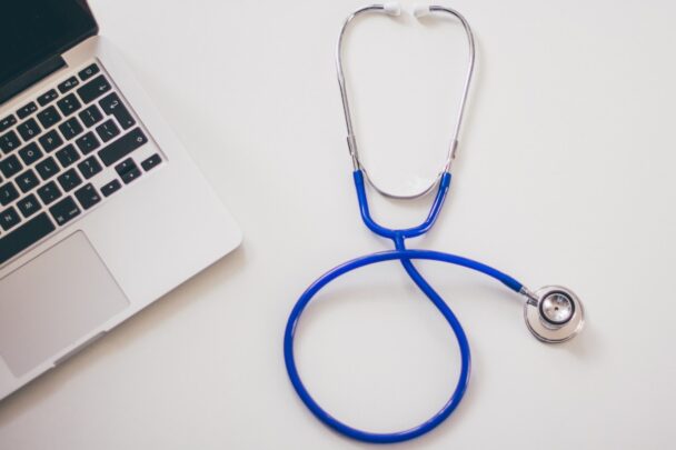 Een tafel met daarop een laptop en ernaast een stethoscoop.
