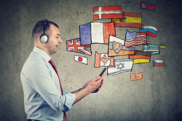 Illustratie van allerlei vlaggen van verschillende landen met op de voorgrond een man met een koptelefoon op en een smartphone in zijn hand.
