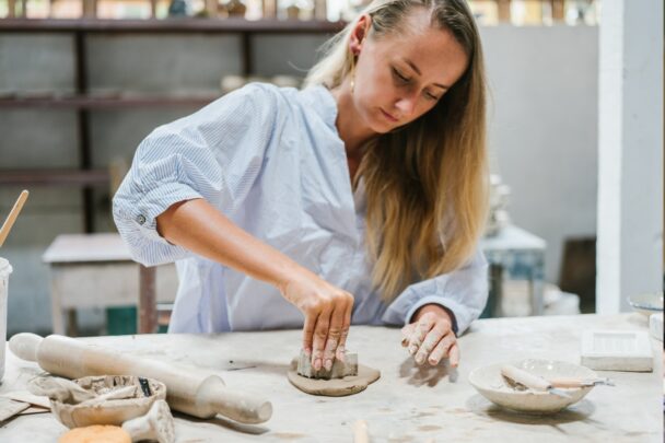 Vrouw werkt met klei en uitsteekvormpjes.