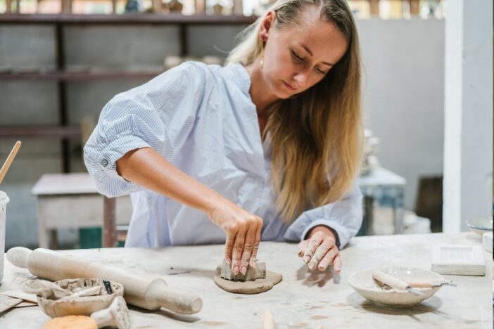 Vrouw werkt met klei en uitsteekvormpjes.