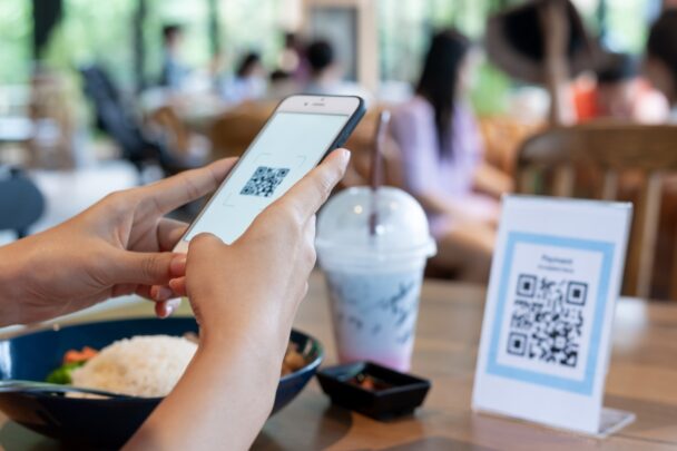 Iemand scant in een restaurant een QR code met zijn smartphone.